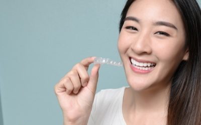 Woman smiling with an Invisalign tray