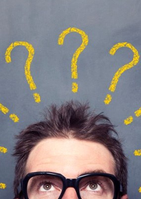 Man standing in front of chalkboard with question marks on it