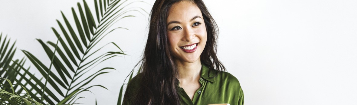 woman smiling next to house plant