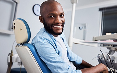 Bearded man sitting in dental chair and smiling. 