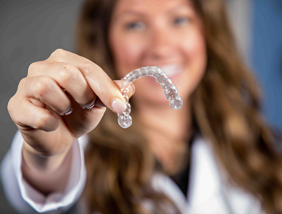 Smiling dental team member holding an Invisalign tray