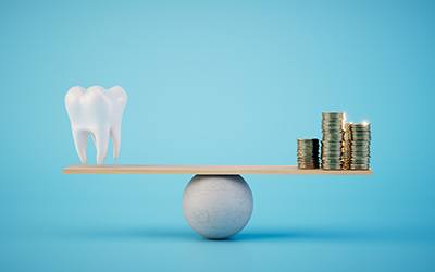 a scale balancing a tooth and coins