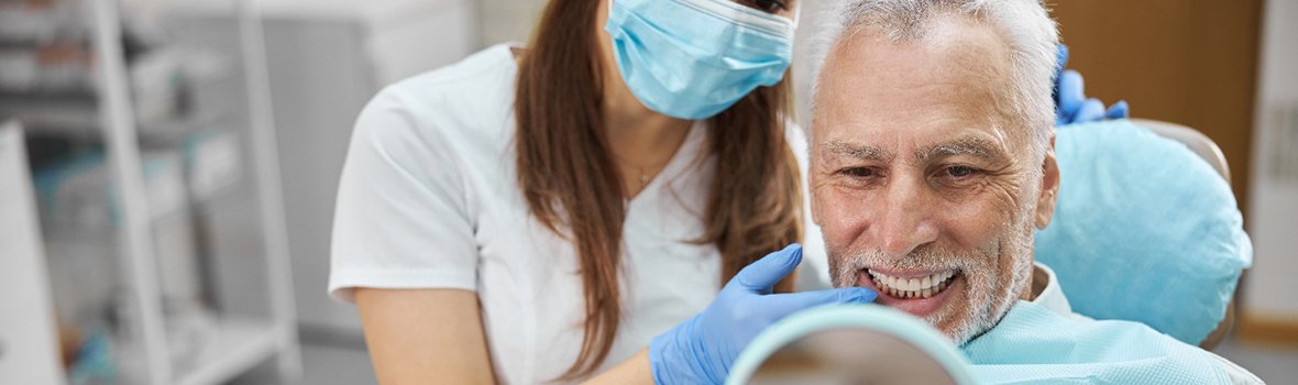 a person looking at their teeth in a mirror in a dental chair