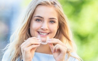 Woman smiling and placing an Invisalign tray