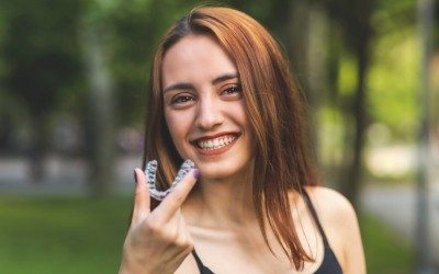 Woman smiling and holding an Invisalign tray