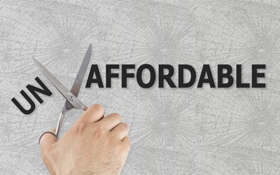 Hand cutting the word “unaffordable” in half