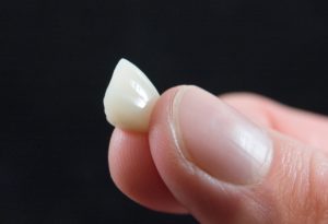 All-ceramic dental crown held in fingertips 