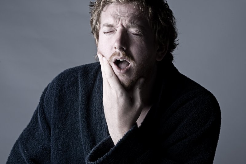 A man holding his jaw due to the pain of dry socket