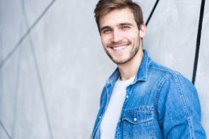 Smiling man leaning up against a wall