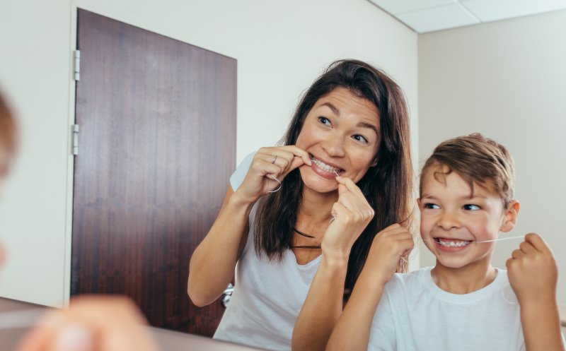 Young patient flossing with mother after children’s dentistry