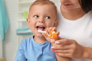 Parent helping child brush his teeth